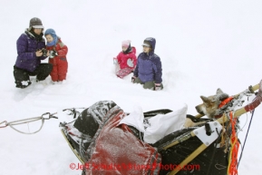 Wednesday March 7, 2012   The Peirce family watches a Trent Herbst dog in the sled basket shorlty after his arrival at the McGrath checkpoint. Iditarod 2012.