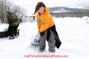 Wednesday March 7, 2012   Takotna resident, 15 year-old Sabrina Anselment volunteers by bringing each musher their food drop bags.  Here she brings Bill Pinkham bag at the Takotna checkpoint Iditarod 2012.