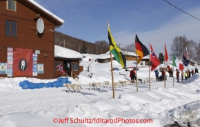 Wednesday March 7, 2012  Jim Lanier runs past the Community center and a row of flags signifying the entrants in the race at the Takotna checkpoint.  Iditarod 2012.