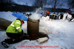 19 year old Takotna volunteer Ryan Goods adds wood to the water fire at the Takotna checkpoint on Thursday March 7, 2013.Iditarod Sled Dog Race 2013Photo by Jeff Schultz copyright 2013 DO NOT REPRODUCE WITHOUT PERMISSION