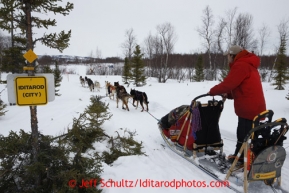 Jason Mackey 's team runs down the trail passing a new sign for Iditarod (City) as he approaches the halfway checkpoint of Iditarod on Thursday March 7, 2013.Iditarod Sled Dog Race 2013Photo by Jeff Schultz copyright 2013 DO NOT REPRODUCE WITHOUT PERMISSION