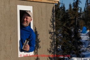 Iditarod volunteer, Brad VanMeter, hangs his head out of the