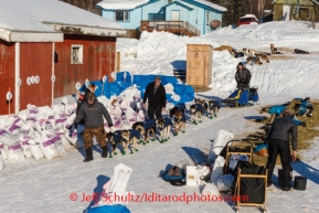 Race judge Kevin Saiki and volunteer comms Dan Greene lead Mike Williams Jr. through the parked dogs on his way out of Ruby after his 8 hour layover on Friday, March 7, during the Iditarod Sled Dog Race 2014.PHOTO (c) BY JEFF SCHULTZ/IditarodPhotos.com -- REPRODUCTION PROHIBITED WITHOUT PERMISSION