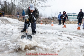 Trail guard Christopher Dement shovels a path for water to run out on the trail near the Alaska Native Hospital during the cermonial start day of Iditarod 2015 in Anchorage, Alaska. Saturday March 7, 2015(C) Jeff Schultz/SchultzPhoto.com - ALL RIGHTS RESERVED DUPLICATION  PROHIBITED  WITHOUT  PERMISSION