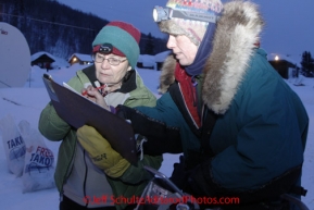 Thursday March, 2012  Perinnial Tokotna checker, Frankie Sayers, signs out Jodi Bailey from her 24 hour layover at the Takotna checkpoint.   Iditarod 2012.