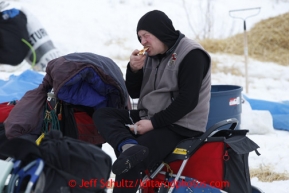 Jerry Sousa eats a snack while sitting on his sled at the halfway checkpoint of Iditarod on Friday March 8, 2013.Iditarod Sled Dog Race 2013Photo by Jeff Schultz copyright 2013 DO NOT REPRODUCE WITHOUT PERMISSION