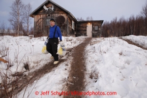 Brad VanMeter takes musher food bags to the trash pile. Due to the warm temperatures volunteers have sandeed the walkway hill trails with dirt at the halfway checkpoint of Iditarod on Friday March 8, 2013.  Iditarod Sled Dog Race 2013Photo by Jeff Schultz copyright 2013 DO NOT REPRODUCE WITHOUT PERMISSION