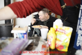 Musher Jim Lanier eats inside a crowded checkpoint cabin at the halfway checkpoint of Iditarod on Friday March 8, 2013.Iditarod Sled Dog Race 2013Photo by Jeff Schultz copyright 2013 DO NOT REPRODUCE WITHOUT PERMISSION