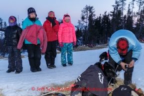 Kids at Koyuk watch Martin Buser put booties on his dogs on Sunday, March 9, during the Iditarod Sled Dog Race 2014.PHOTO (c) BY JEFF SCHULTZ/IditarodPhotos.com -- REPRODUCTION PROHIBITED WITHOUT PERMISSION