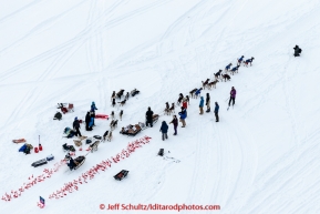 A team passes Jeff King as he changes a dog at Camp Flamingo on the Tanana River after leaving the start line at Pike's Landing in Fairbanks on Monday March 9, 2015 during Iditarod 2015.(C) Jeff Schultz/SchultzPhoto.com - ALL RIGHTS RESERVED DUPLICATION  PROHIBITED  WITHOUT  PERMISSION