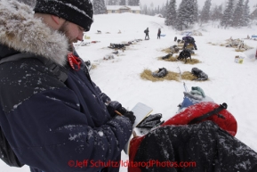 Monday March 5, 2012  Veterinarian Chris Kleine checks Art Church's dog team diary at the Finger Lake checkpoint during Iditarod 2012.