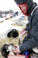 Tuesday March 6, 2012 Nicholas Petit gives a massage to his dog, Helga, at the Nikolai checkpoint, Iditarod 2012.