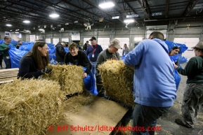 Volunteers bag, palletize and add postage to 1500 bales of straw at Airland Transport in Anchorage to be sent out to the 22 checkpoints along the Iditarod trail Thursday, Feb. 7, 2013.