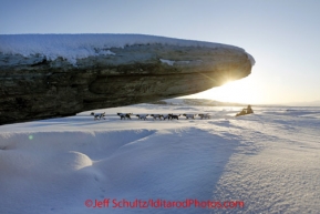 Sunday March 11, 2012  Rohn Buser runs past a driftwood log after leaving Unalakleet. Iditarod 2012.