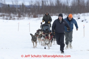 GCI sponsor representative Mark Calrson and Donlin Gold representative Ricky Ciletti guide Rudy Demoski 's team to a parking place at the halfway checkpoint of Iditarod on Friday March 8, 2013.Iditarod Sled Dog Race 2013Photo by Jeff Schultz copyright 2013 DO NOT REPRODUCE WITHOUT PERMISSION