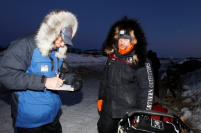 Race Judge Larry Westlake checks in Allen Moore at dawn at Unalakleet on Monday morning during Iditarod 2011