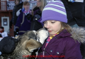 Thursday March 15, 2012   Young Stephanie Daniel from Nome gets a kiss from a Buser dog in the finish chute shortly after Rohn and Martin finished at a tie for 18th place. Iditarod 2012.