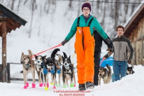 Musher and checkpoint helper Meredith Mapes leads Jason Campeau's team down the hill in preparation to leave from his mandatory 24-hour layover in the morning at the Takotna checkpoint during the 2019 Iditarod on Thursday, March 7th 2019.Photo by Jeff Schultz/  (C) 2019  ALL RIGHTS RESERVED