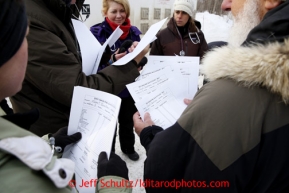 Volunteer veterinarians shuffle paperwork for sled dogs as they get ready for mandatory examinations in Wasilla Wednesday, Feb. 27, 2013.