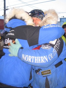 Rohn and Martin Buser Hug at Burled Arch in Nome