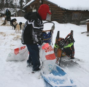 This young helper in Shageluk lifts a drop bag off the blue toboggan.